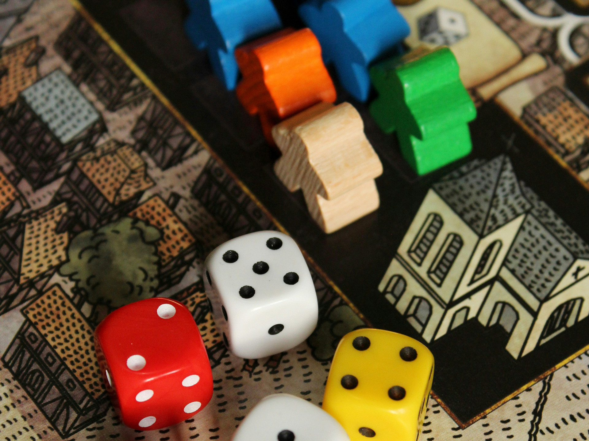 Würfel und Spielfiguren auf einem Brettspiel.