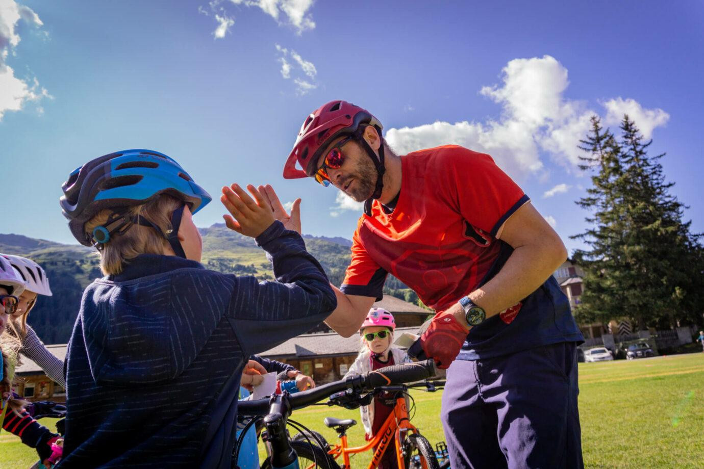Erwachsener gibt einem Kind beim Radfahren ein High-Five.