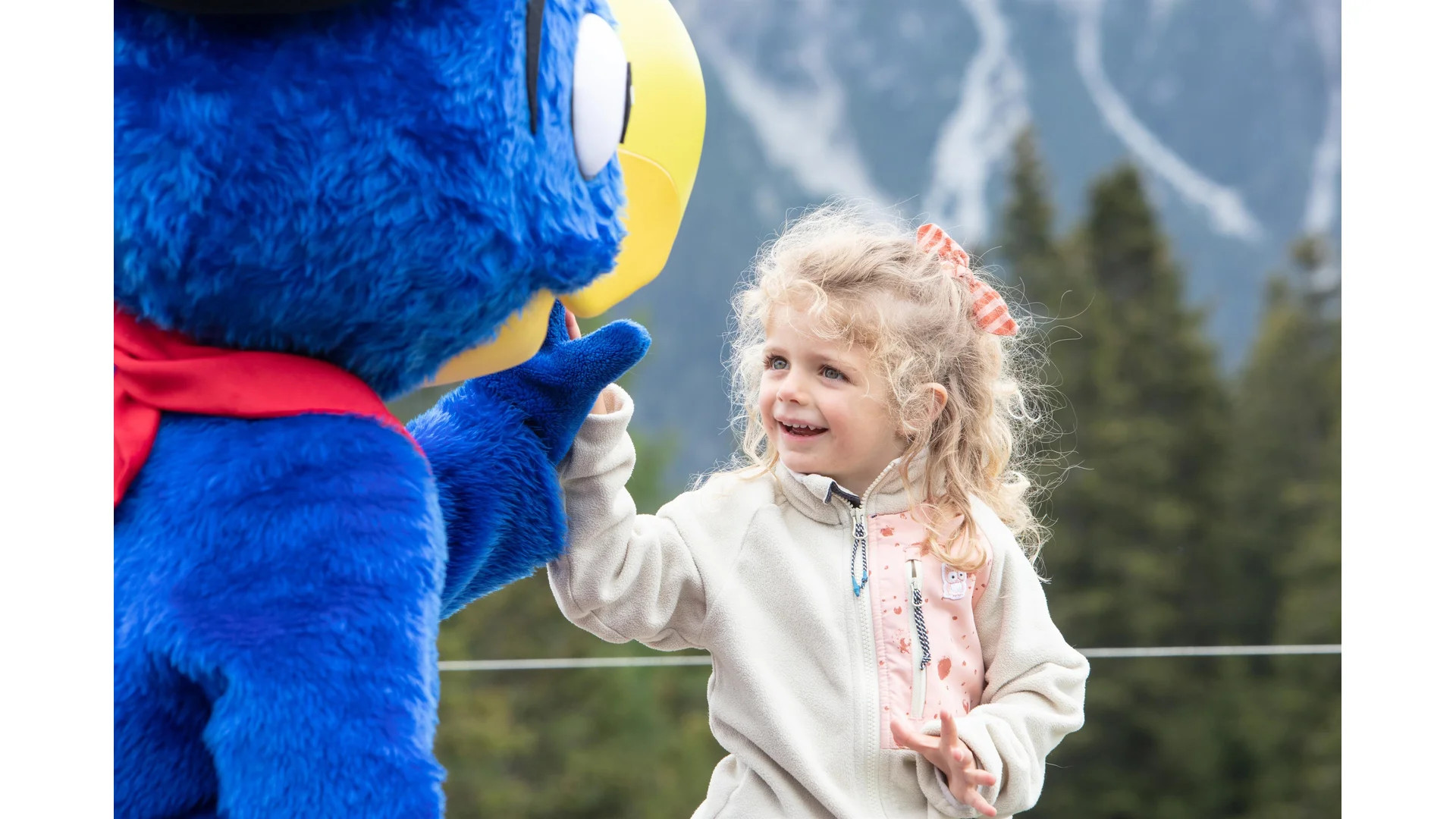 Kind interagiert mit einem verkleideten Maskottchen im Freien.