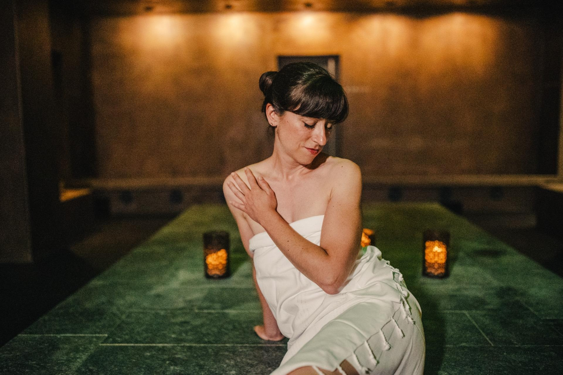 Frau in einem Spa-Bereich auf einer Liege mit Kerzenlicht.