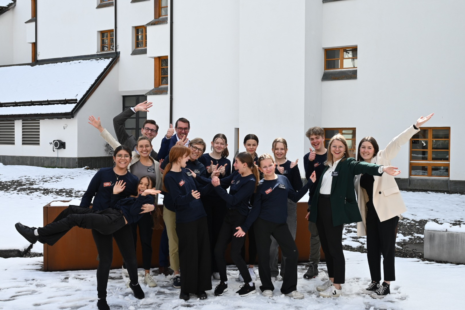 Gruppe gut gelaunter Mitarbeitender, die draussen im Schnee posieren und ausgelassen in die Kamera lachen.