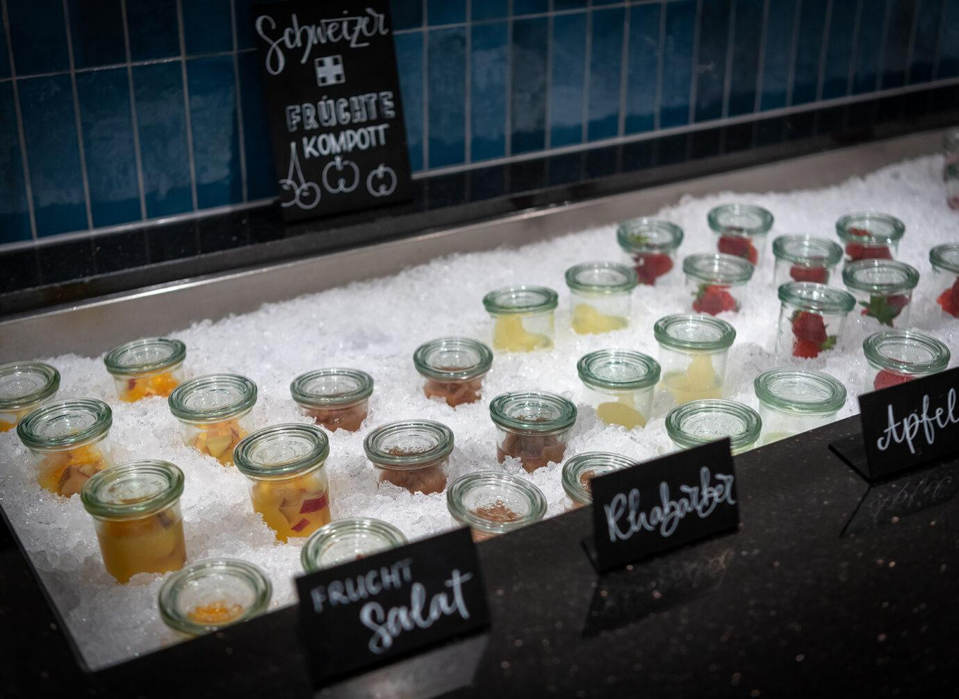 Kleine Gläser mit Schweizer Früchtkompott und Fruchtsalat stehen gekühlt auf Eis im Buffetbereich des Hotels Schweizerhof Lenzerheide.