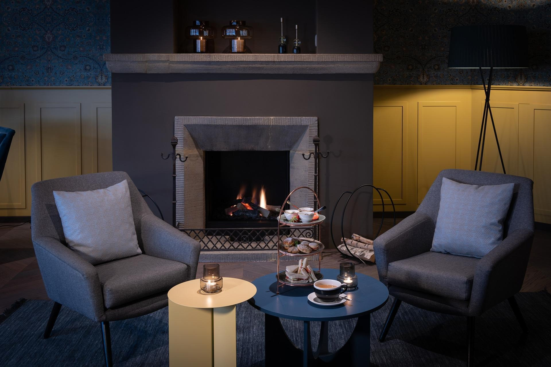 Sitzlounge vor einem Kamin mit Kerzen und Süssgebäck auf dem Beistelltisch,