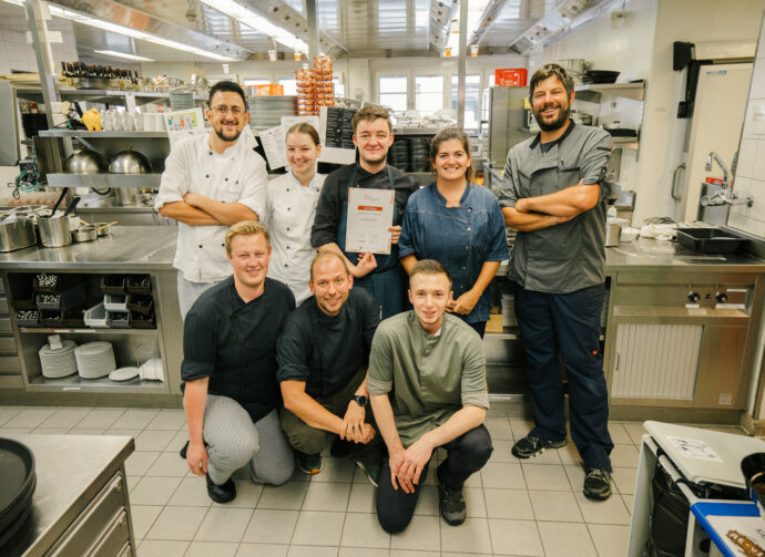 Mitarbeitenden der Küche die in der Gruppe posieren und ein Zertifikat in der Hand halten.
