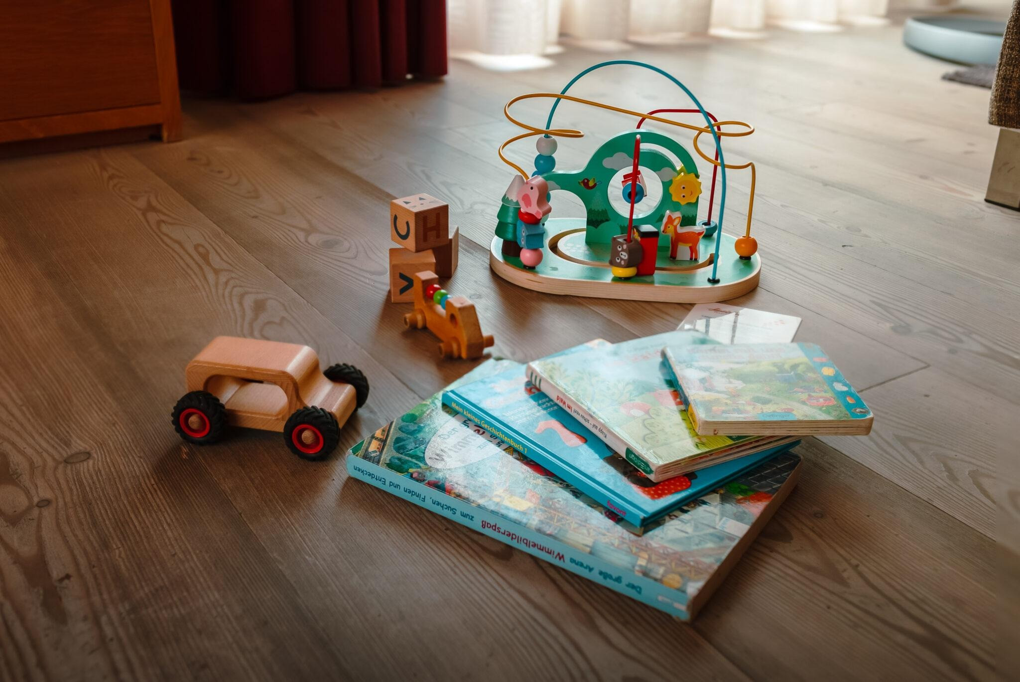 Kinderspielzeug und Bilderbücher liegen auf einem Holzboden.