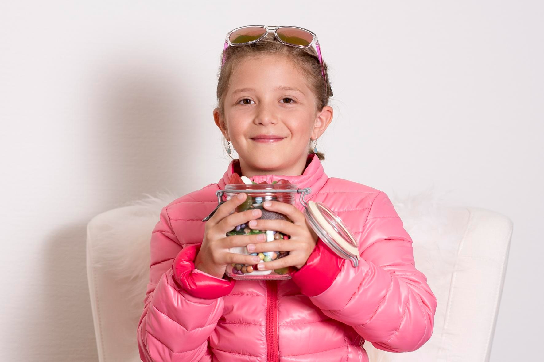 Ein Kind hält ein Glas mit Süssigkeiten in den Händen.
