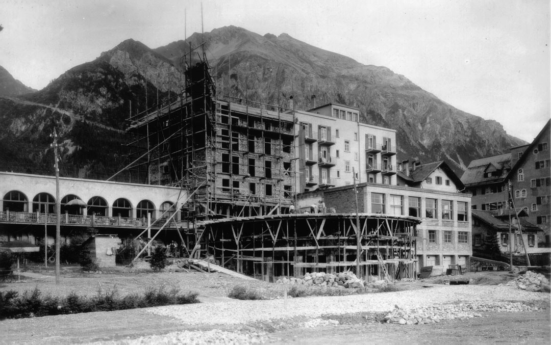 Historische Aufnahme vom Bau des Hotel Schweizerhof in Lenzerheide vor alpiner Bergkulisse.