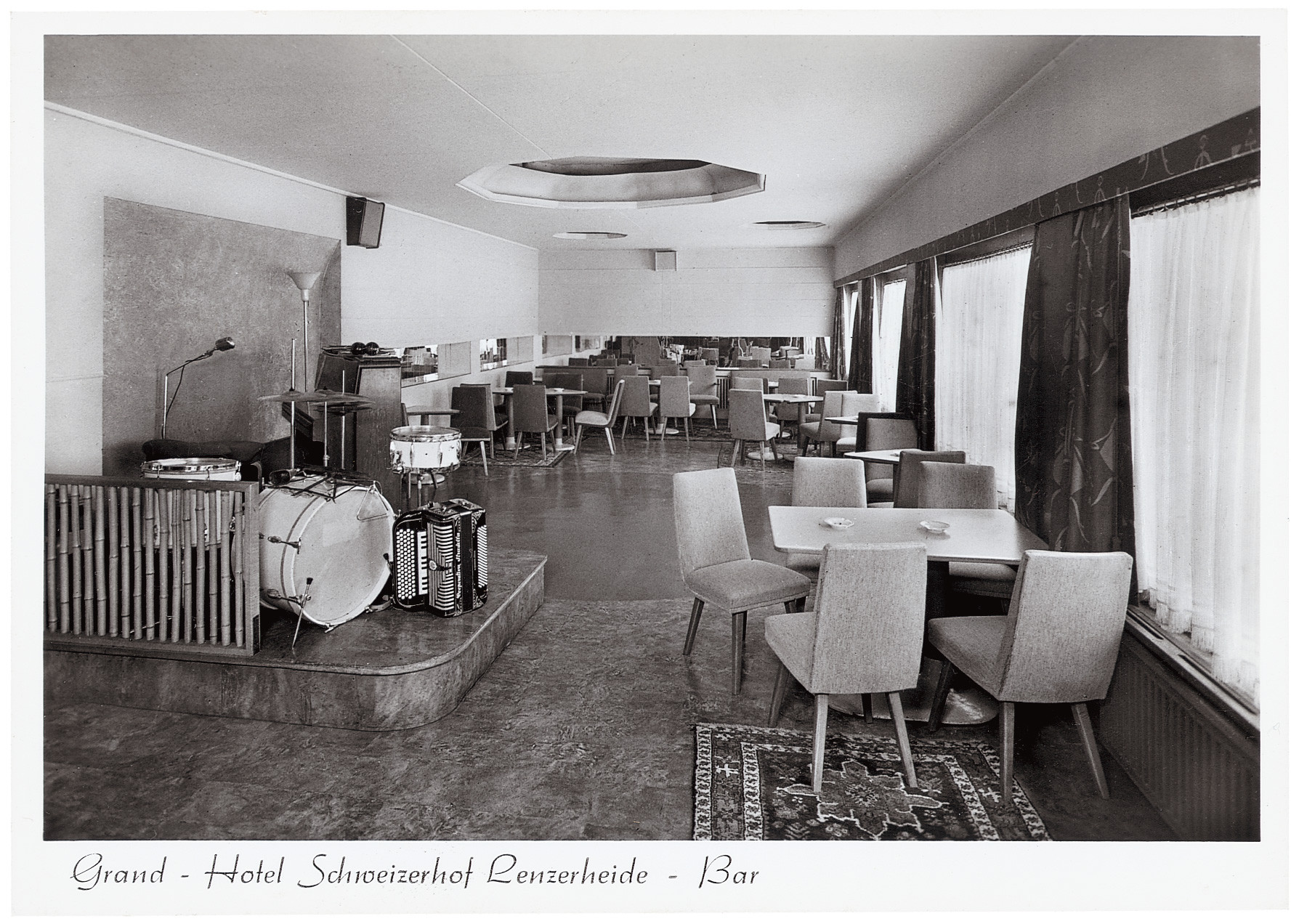 Historische Hotelbar im Grand Hotel Schweizerhof Lenzerheide mit Bühne, Instrumenten und retrobestuhltem Loungebereich.