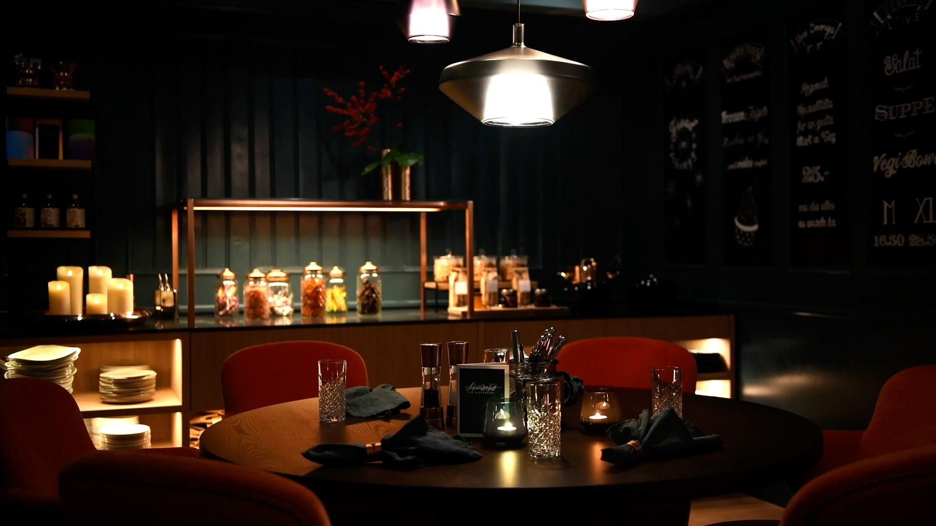 Gemütliche Aufnahme der Bar mit gedecktem Esstisch und im Hintergrund Kerzen und Selbstbedienungsablage.