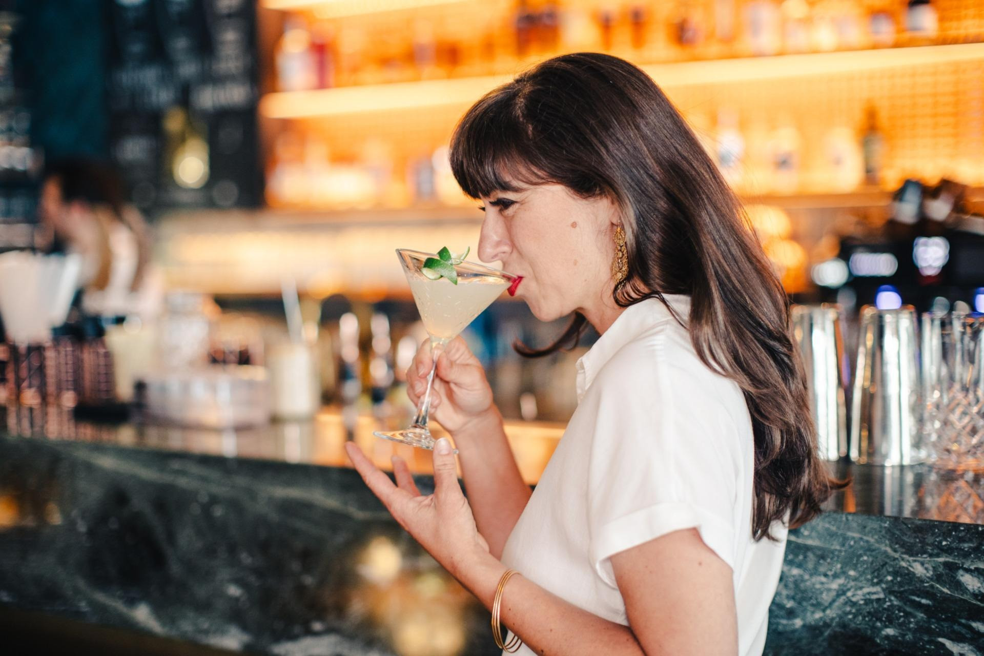 Frau die an der Bar aus einem Martini-Glas trinkt
