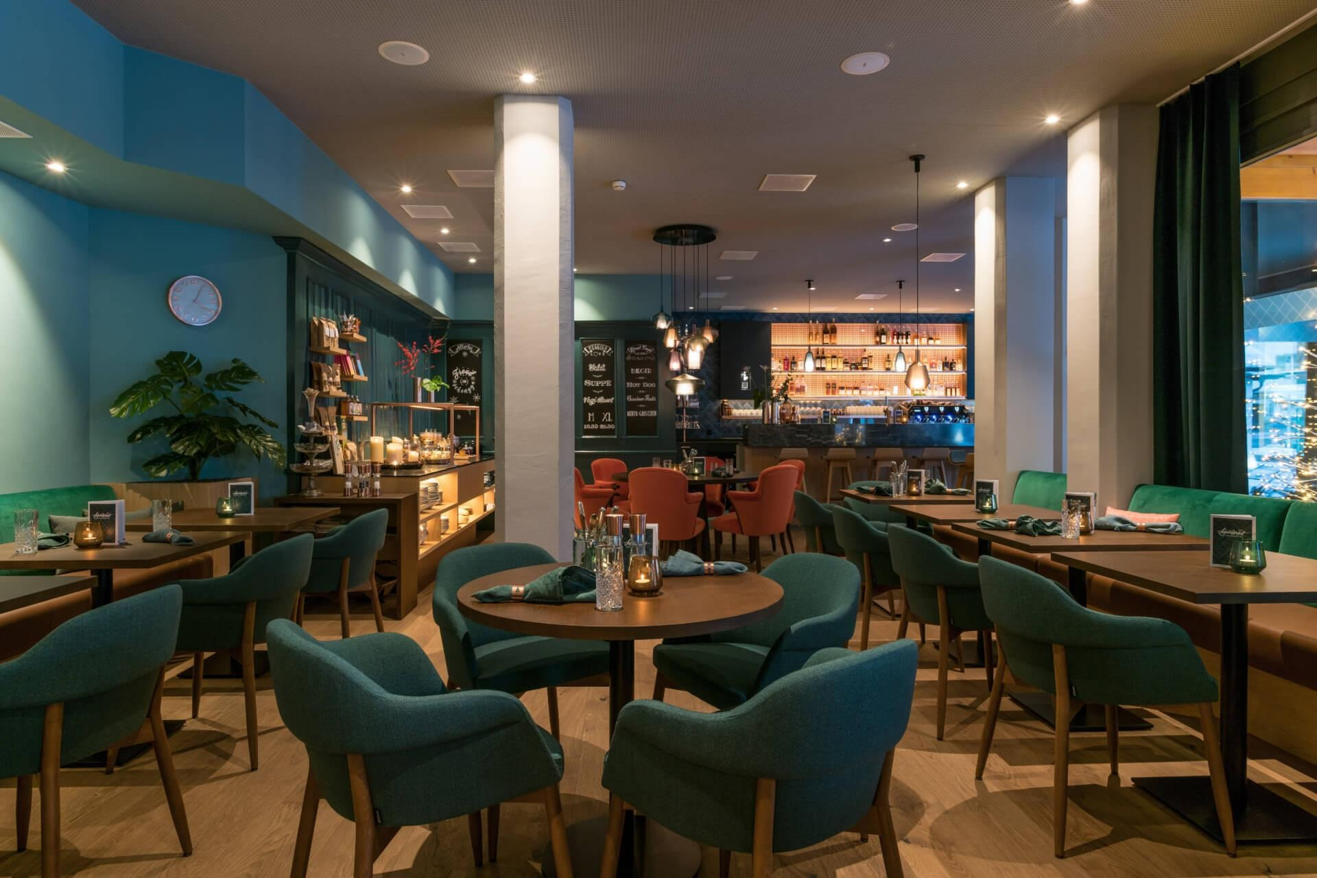 Modern dekorierter Essensbereich im Hotel mit Esstischen und Selbstbedienungstheke sowie Blick auf die Bar