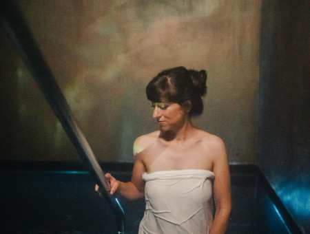 „Frau steigt in das stimmungsvoll beleuchtete Tauchbecken im Wellnessbereich des Hotel Schweizerhof Lenzerheide und genießt die erfrischende Abkühlung