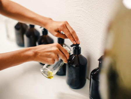 Nahaufnahme einer Hand, die Massageöl in ein Glas gießt – Vorbereitung einer Behandlung im Spa des Hotel Schweizerhof Lenzerheide