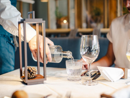 Servicepersonal schenkt Wasser ein im Restaurant des Hotel Schweizerhof Lenzerheide – Gastfreundschaft mit Stil