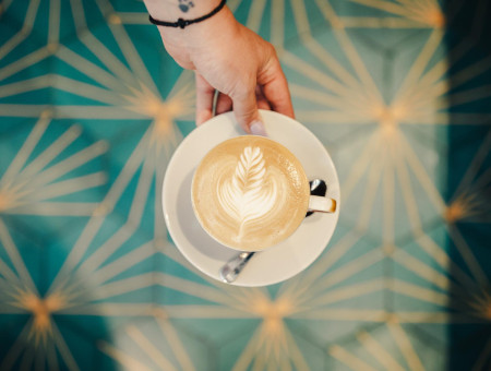 Barista serviert kunstvoll zubereiteten Cappuccino im Hotel Schweizerhof Lenzerheide – Kaffeegenuss mit Stil im gemütlichen Ambiente