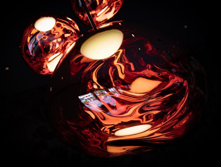 „Detailaufnahme einer kunstvollen Leuchte im Wellnessbereich des Hotel Schweizerhof Lenzerheide mit warmem, rotgoldenem Lichtspiel für stimmungsvolle Atmosphäre