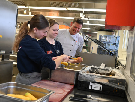 Schülerinnen schälen Gemüse in der Küche – praxisnahes Lernen beim Behind the Scenes Programm im Hotel Schweizerhof Lenzerheide