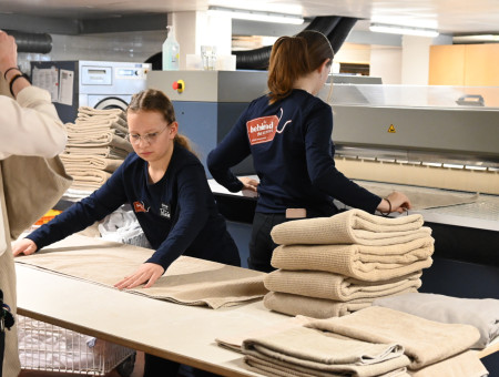 Teilnehmerinnen des Behind the Scenes Projekts falten Wäsche in der Hotel-Lingerie im Schweizerhof Lenzerheide