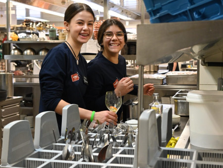 wei Schülerinnen des Behind the Scenes Programms in der Hotelküche des Schweizerhof Lenzerheide beim Abwaschen und Lachen