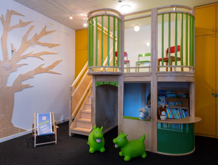 Kinderparadies im Hotel Schweizerhof Lenzerheide mit Spielecke, Bücherregal, bunten Spieltieren und Kletterbereich