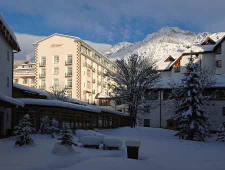 Hotel Schweizerhof Lenzerheide im Winter mit verschneitem Innenhof, Alpenpanorama und gemütlicher Atmosphäre inmitten der Berge