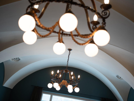 Kunstvoller Kronleuchter unter Gewölbedecke im Hotel Schweizerhof Lenzerheide – stilvolles Lichtdesign