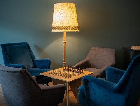 Einladende Sitzecke mit Schachspiel und Stehlampe im Hotel Schweizerhof Lenzerheide – stilvoller Rückzugsort