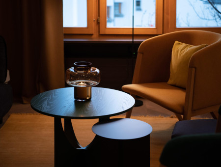 Detailaufnahme eines elegant gedeckten Beistelltisches mit Kerze und Sessel im Hotel Schweizerhof Lenzerheide – stilvolle Gemütlichkeit