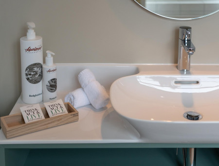 Waschbecken im Nostalchic Badezimmer des Hotel Schweizerhof Lenzerheide mit nachhaltigen Pflegeprodukten und Handtüchern