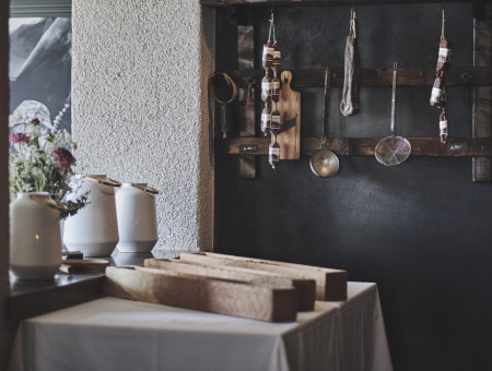 Dekorative Ecke im Scalottas Terroir Lenzerheide mit Trockenwürsten, Kochutensilien und frischen Blumen – authentisches Alpenambiente