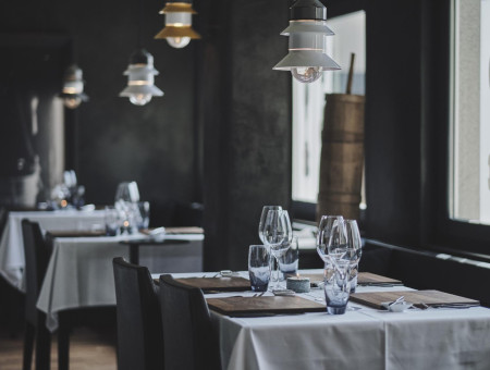 Dunkler, eleganter Gastraum im Scalottas Terroir Lenzerheide mit stimmungsvoller Beleuchtung und modernen Holzelementen