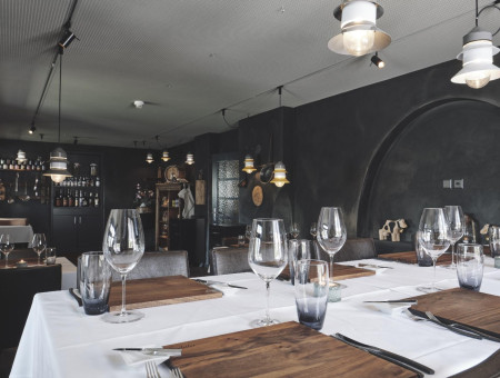 Innenraum des Scalottas Terroir Lenzerheide mit modernen Lampen, Holzboden und liebevoll eingedeckten Tischen für Feinschmecker