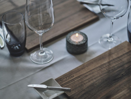 Detailaufnahme eines gedeckten Tisches im Scalottas Terroir Lenzerheide mit Holzbrett, Weingläsern und Kerze – elegantes Fine Dining Ambiente
