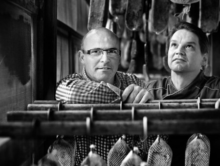 Zwei Männer im Reiferaum zwischen aufgehängtem Schinken – regionale Fleischveredelung im Scalottas Terroir Lenzerheide