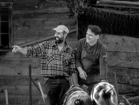 Zwei Männer mit Schweinen auf Bauernhof – verantwortungsvolle Tierhaltung im Scalottas Terroir Lenzerheide