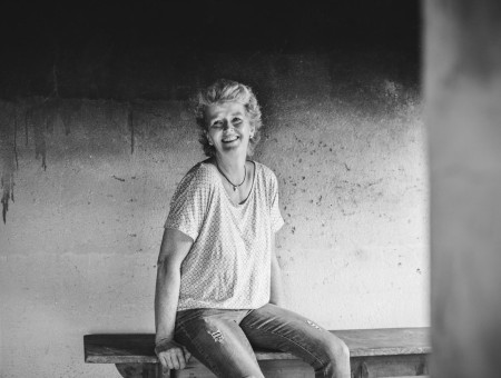 Porträt einer lächelnden Frau auf einer Holzbank – authentische Produzentin des Scalottas Terroir Lenzerheide in traditioneller Umgebung