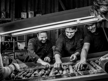 Schwarzweißaufnahme von Köchen und Produzenten beim Aussortieren von Kartoffeln – gelebte Regionalität und Teamarbeit im Scalottas Terroir Lenzerheide