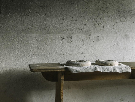 Rustikale Holzbank mit Brotteiglingen vor rauer Wand – authentische Backatmosphäre im Scalottas Terroir Lenzerheide