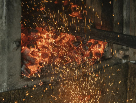 Glühende Kohlen im Holzofen mit aufsteigenden Funken – traditionelle Backkunst im Scalottas Terroir Lenzerheide