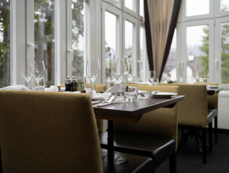 Heller Wintergarten im Restaurant im Hotel Schweizerhof Lenzerheide mit grossen Fenstern und elegantem Ambiente