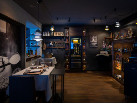 „Innenaufnahme des Scalottas Terroir Lenzerheide mit gedecktem Tisch, Feinkostregalen und stimmungsvoller Beleuchtung