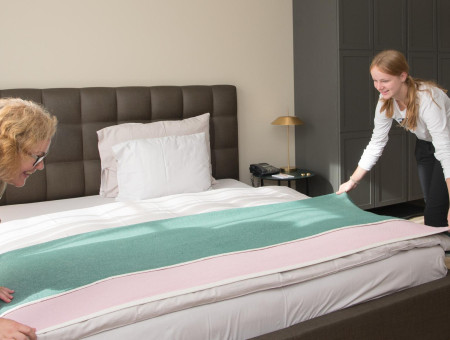 Teilnehmerin des Behind the Scenes Projekts hilft beim Bettenmachen im Hotel Schweizerhof Lenzerheide