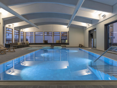 Indoorpool im Hotel Schweizerhof Lenzerheide mit modernem Wellnessbereich und großzügiger Architektur für pure Erholung