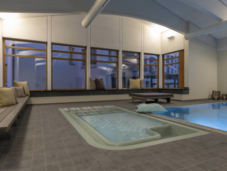 Whirlpool und Relaxzone im Spa-Bereich des Hotel Schweizerhof Lenzerheide mit stilvollen Sitzgelegenheiten und warmem Lichtambiente