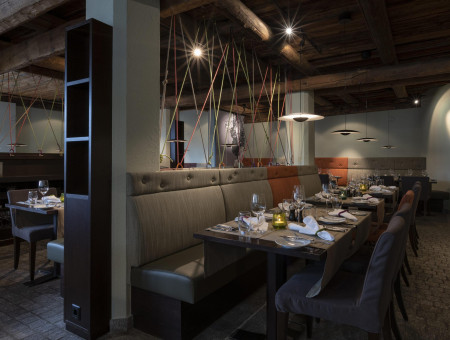 Restaurant im Hotel Schweizerhof Lenzerheide mit rustikalem Design, Holzbalken und stilvoller Beleuchtung für genussvolle Abende