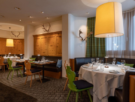 Gemütliches Restaurant im Hotel Schweizerhof Lenzerheide mit Holzwänden, modernen Akzenten und traditionellem Charme