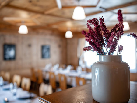 Dekorative Blumenvase in der Arvenstube des Scalottas Terroir Lenzerheide mit stimmungsvoller Atmosphäre und Holzelementen