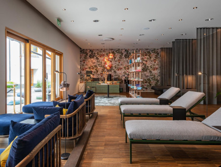 Ruheraum im Wellnessbereich des Hotel Schweizerhof Lenzerheide mit modernen Liegen, gemütlicher Atmosphäre und Blick auf die Terrasse