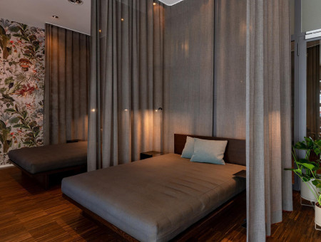 Ruheraum im Wellnessbereich des Hotel Schweizerhof Lenzerheide mit abgetrennten Liegebetten, sanfter Beleuchtung und stilvollem Design