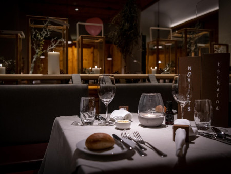 Stimmungsvoll gedeckter Tisch im Restaurant im Hotel Schweizerhof Lenzerheide mit Kerzenschein und edlem Gedeck